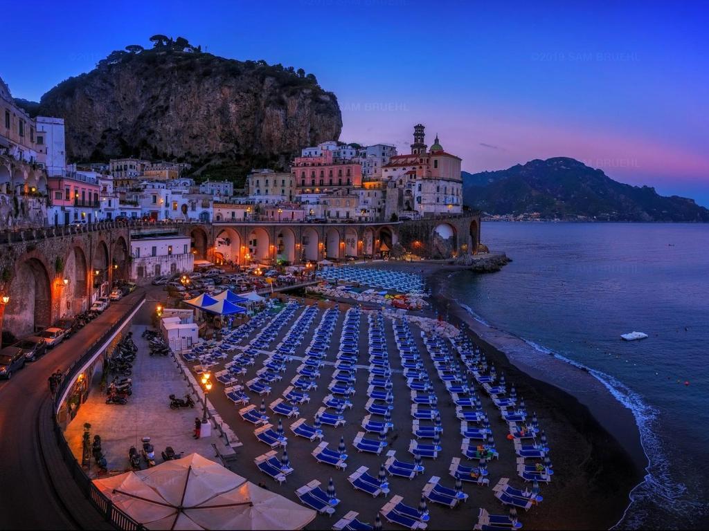 - un groupe de parasols et de chaises sur une plage la nuit dans l'établissement G&G- Amalfi coast - sea view - beach, à Atrani