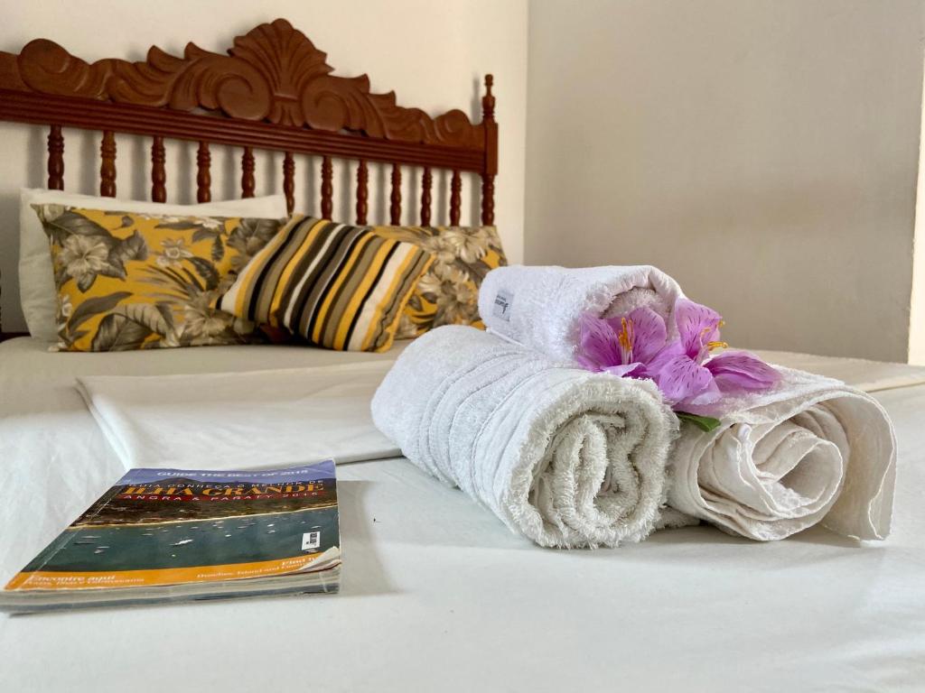 een handdoek op een bed naast een boek bij Casa da Polly IG in Abraão
