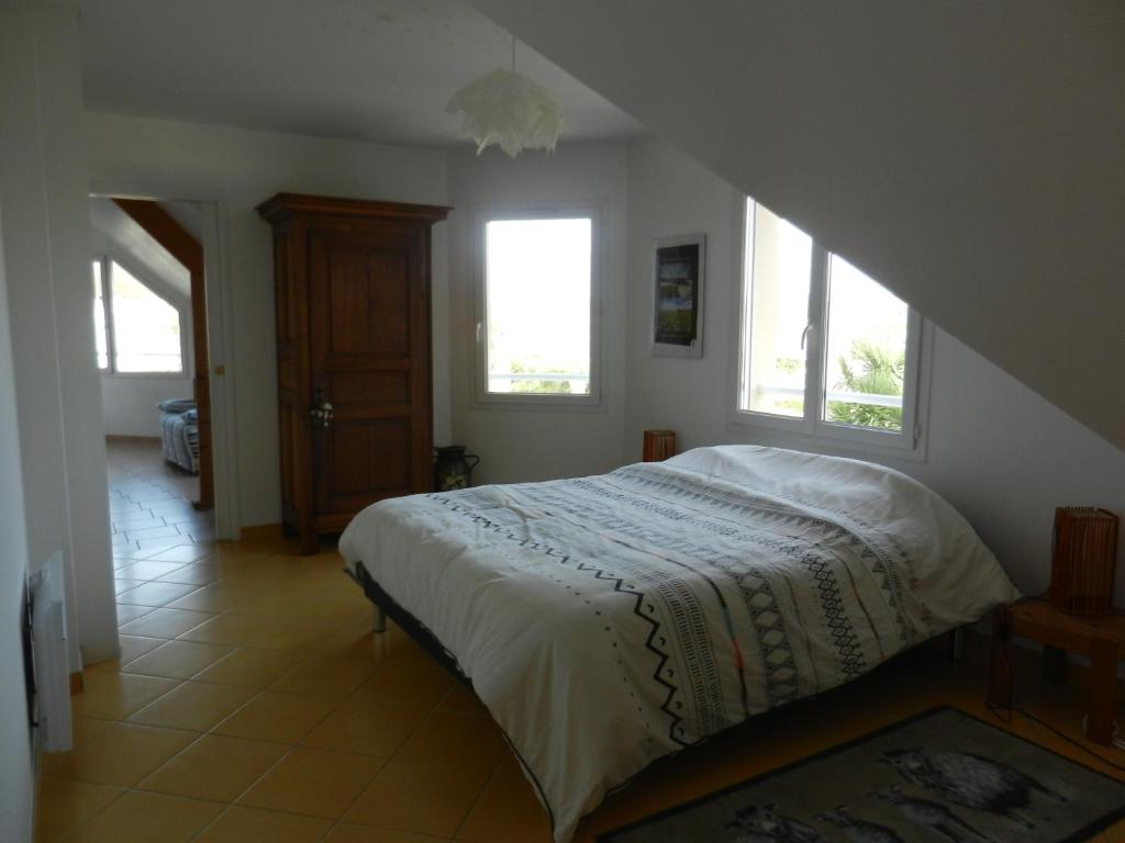 a bedroom with a bed and two windows at VILLA THEDIEBERT in Barneville-Carteret