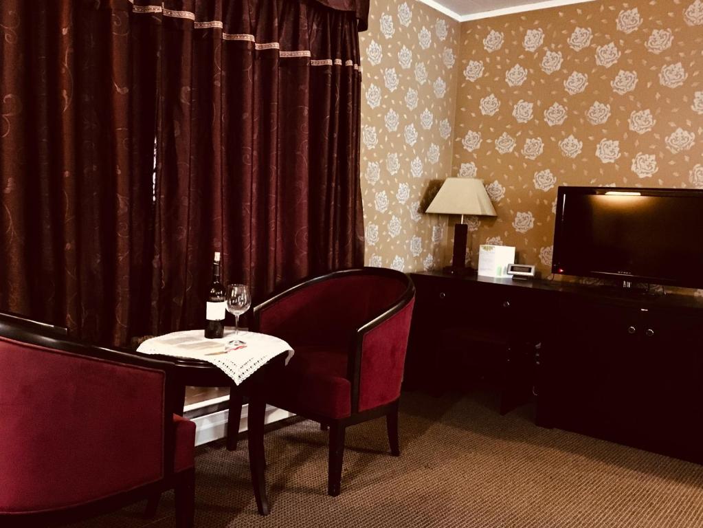 a room with a table with a wine glass and a television at Alpine Inn & Suites in Revelstoke