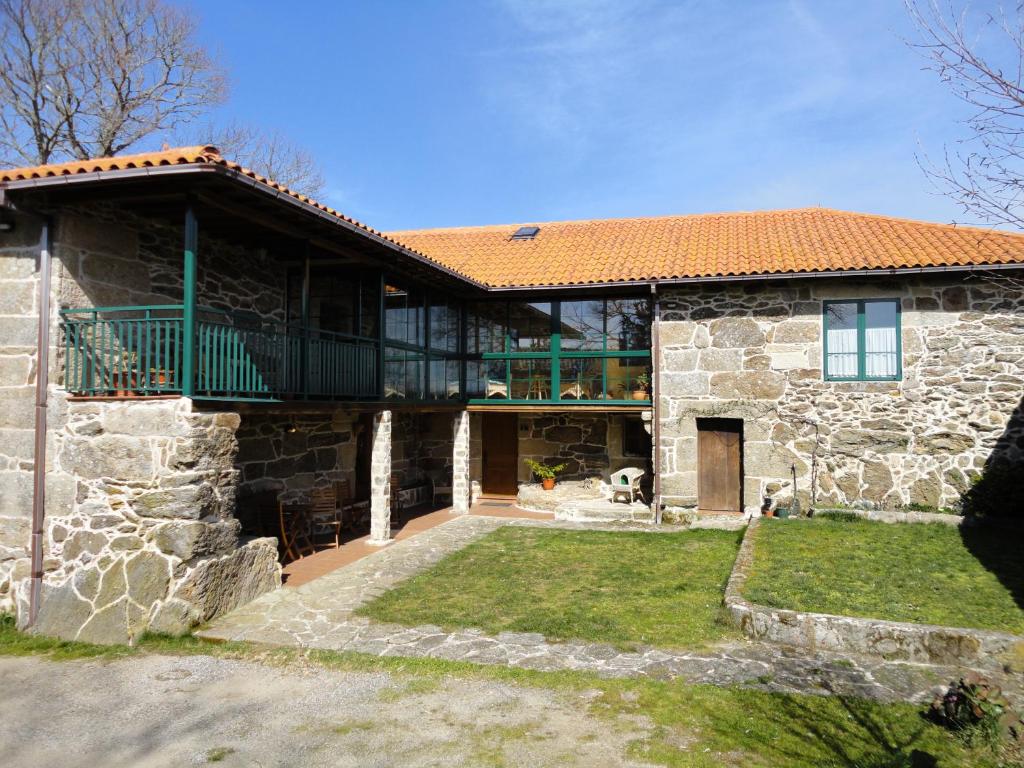 Cette grande maison en pierre possède une grande fenêtre. dans l'établissement Casa Rural Rectoral de Candás, à Rairiz de Veiga