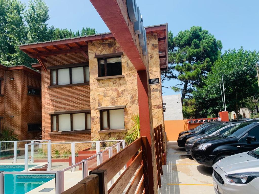 a building with cars parked in a parking lot at Departamentos Le Forêt in Mar de Ajó