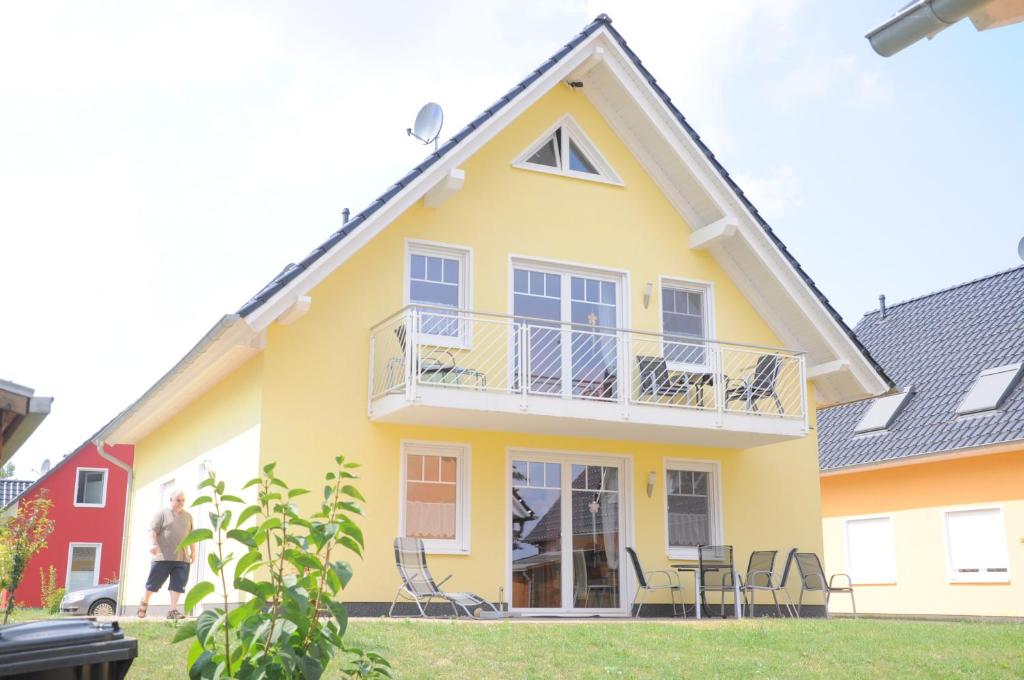 a yellow house with chairs in front of it at Ferienhaus Müritzsonne / EG-Appartement in Marienfelde