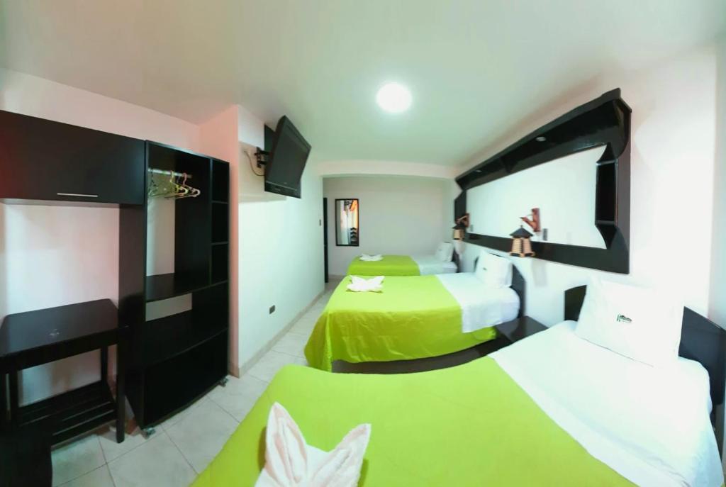 Dos camas en una habitación de hotel con verde y blanco en Hotel Ñuñurco Travellers, en Chachapoyas