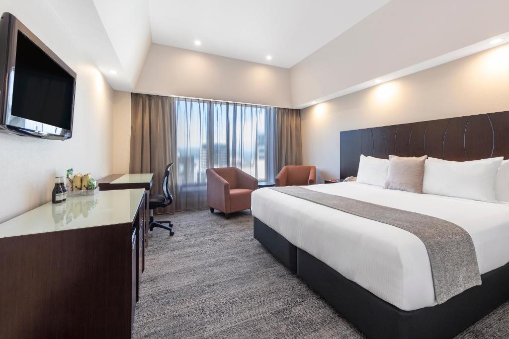 Una habitación de hotel con una cama y un televisor de pantalla plana. en James Cook Hotel Grand Chancellor, en Wellington