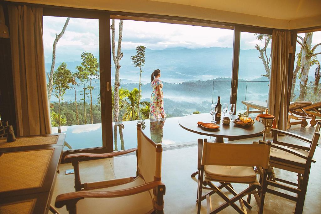 a woman walking around a room with a table and chairs at Aarunya Nature Resort and Spa in Kandy