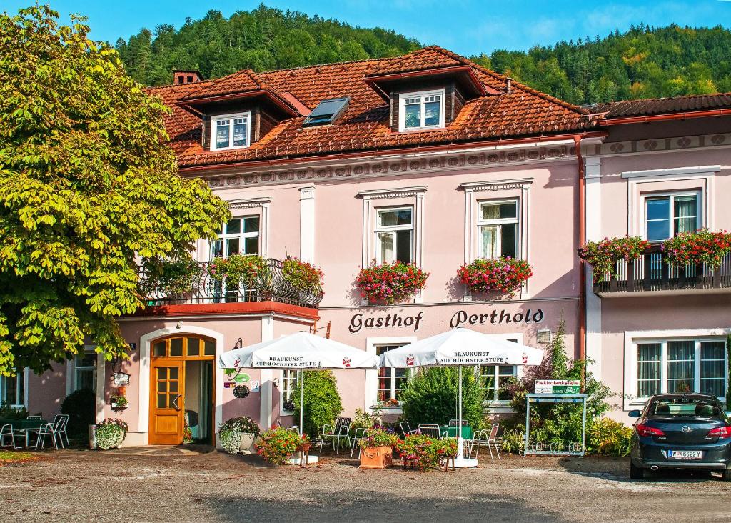 um edifício cor-de-rosa com mesas e cadeiras à sua frente em Gasthof Zum Niederhaus - Familie Perthold em Sankt Aegyd am Neuwalde