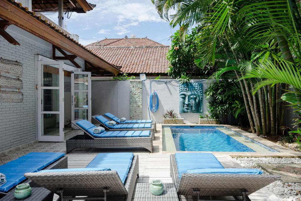 a backyard with a pool and chairs and a house at Tropical House - Legian in Legian