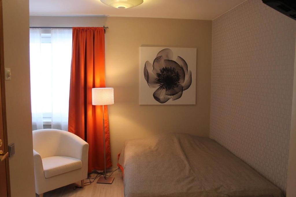 een slaapkamer met een bed, een stoel en een raam bij Motelli Jätkänkolo in Pello