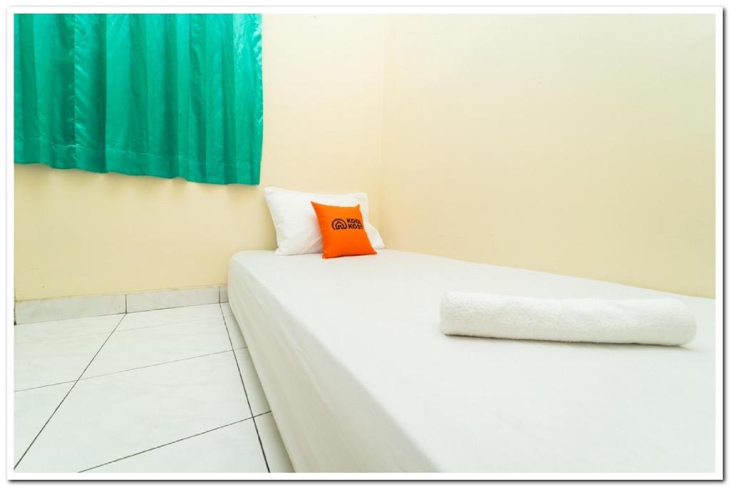 a white bed with an orange pillow on it at Koolkost Near Universitas Maranatha 2 Bandung - Minimum Stay 30 Nights in Bandung