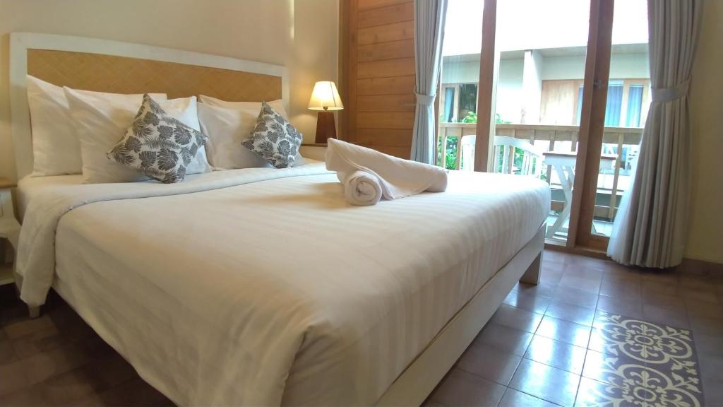 2 bedden in een hotelkamer met een groot raam bij Jukung Guest House in Sanur