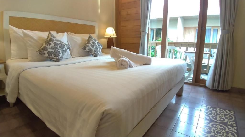 two beds in a hotel room with a large window at Jukung Guest House in Sanur