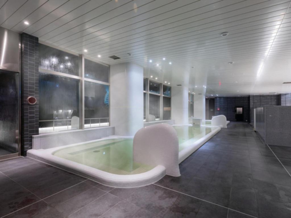 a bathroom with a tub with white chairs in it at LIBER HOTEL Osaka in Osaka
