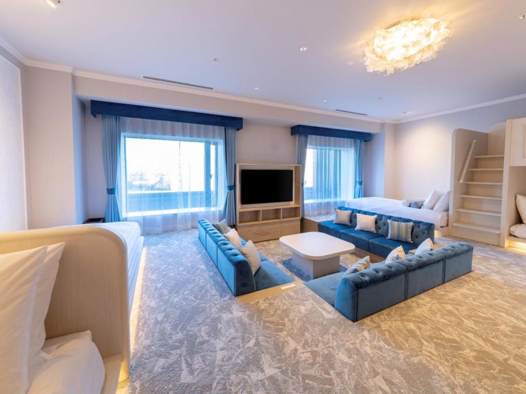 a large living room with blue couches and a television at LIBER HOTEL Osaka in Osaka