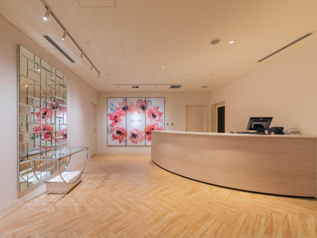 a lobby with a reception desk and a painting on the wall at LIBER HOTEL Osaka in Osaka
