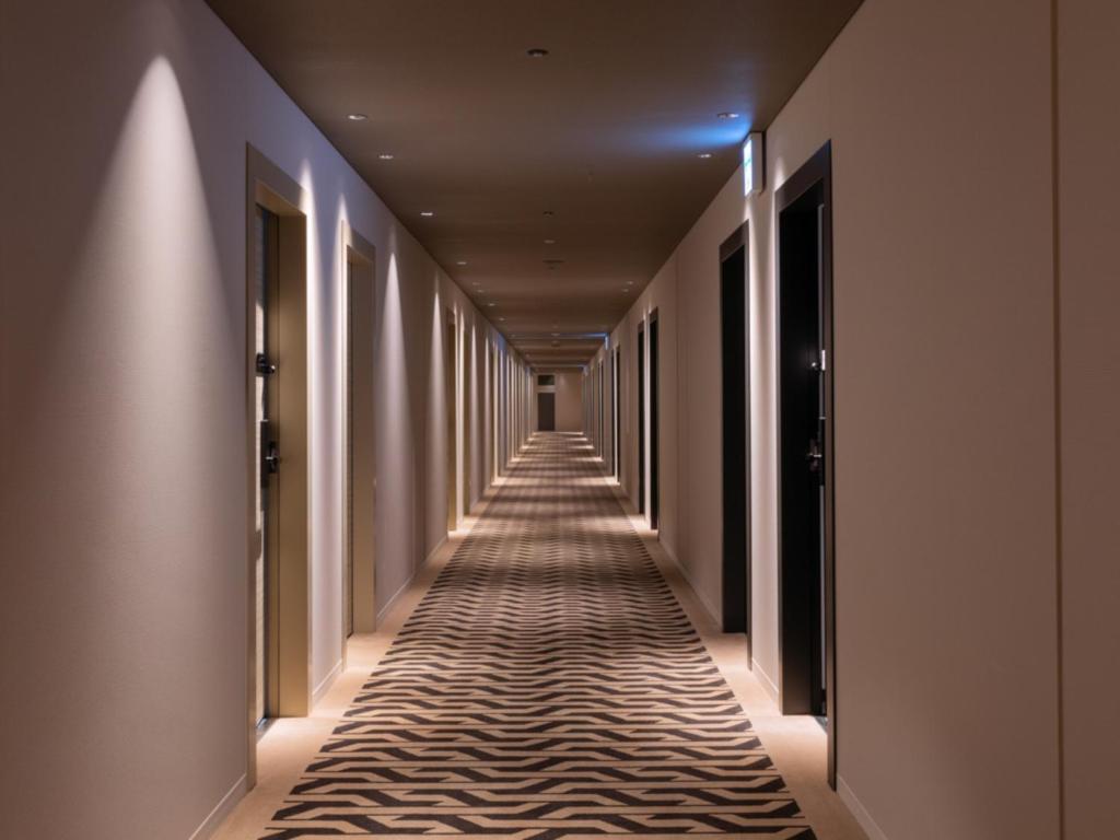 a corridor of a hotel with a carpeted hallway at LIBER HOTEL Osaka in Osaka