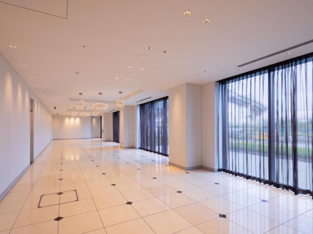 an empty corridor in a building with large windows at LIBER HOTEL Osaka in Osaka