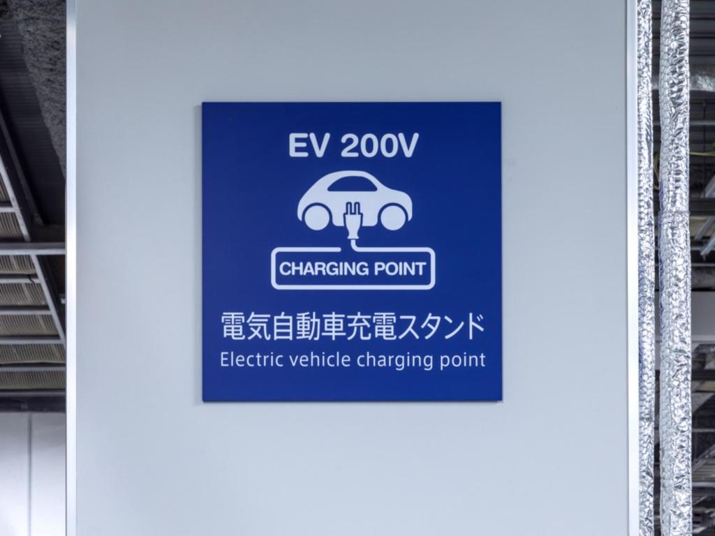 a sign for a car charging point at a train station at LIBER HOTEL Osaka in Osaka