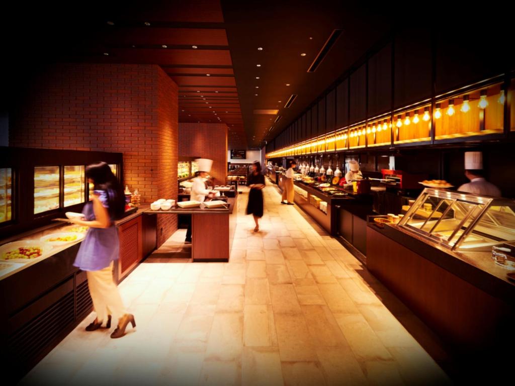 a woman standing in front of a buffet line in a restaurant at LIBER HOTEL Osaka in Osaka