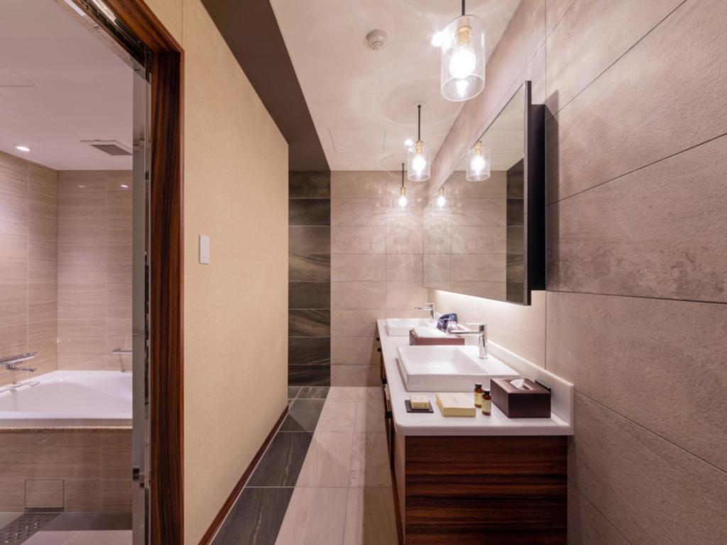 a bathroom with two sinks and a bath tub at LIBER HOTEL Osaka in Osaka