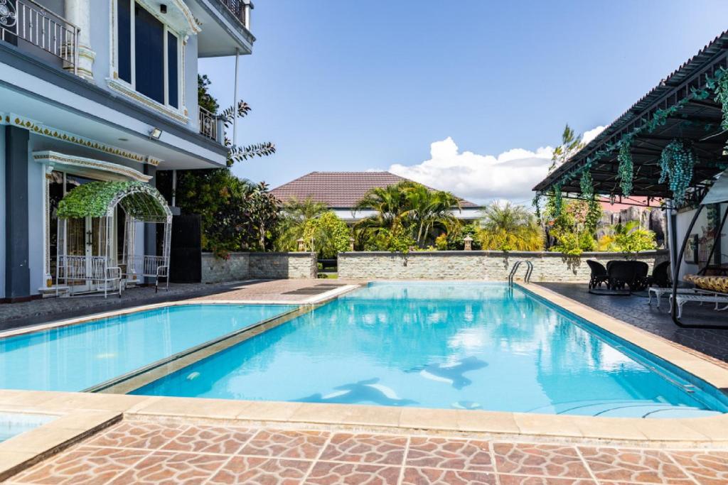 a swimming pool in front of a house at RedDoorz Premium @ Sea Residence Manado in Manado