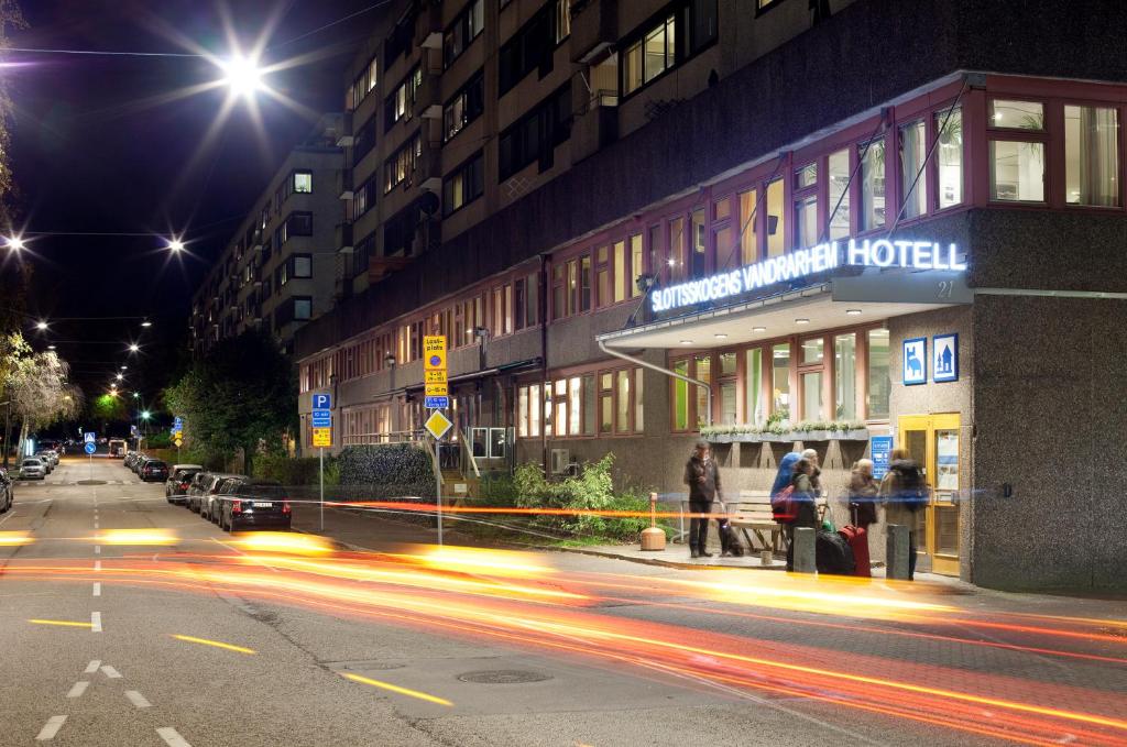 uma rua da cidade à noite com pessoas em pé fora de um hotel em Slottsskogen Hotel em Gotemburgo