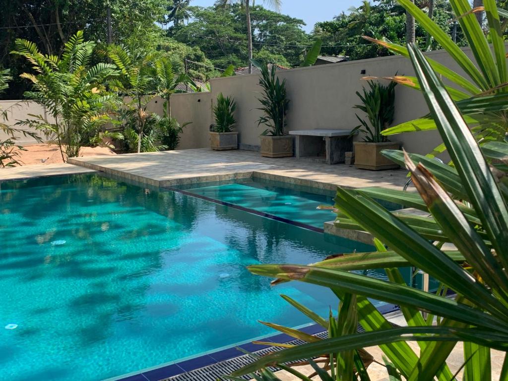a swimming pool with blue water in a yard at Anveela in Beruwala
