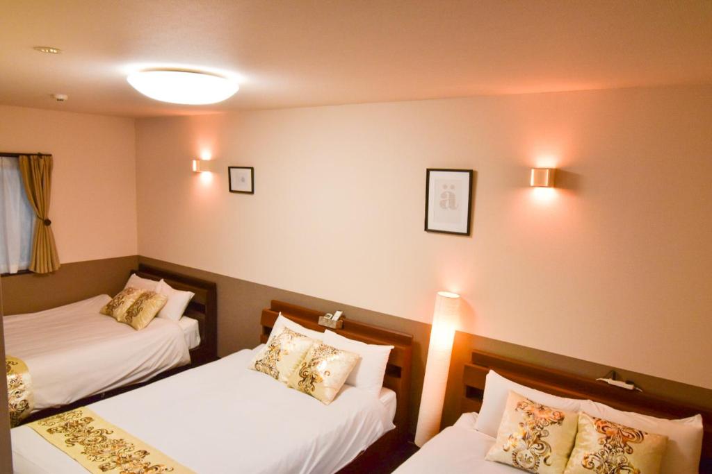 a hotel room with two beds and lights on the wall at Guest House One More Heart Kyoto Station South 1 in Kyoto