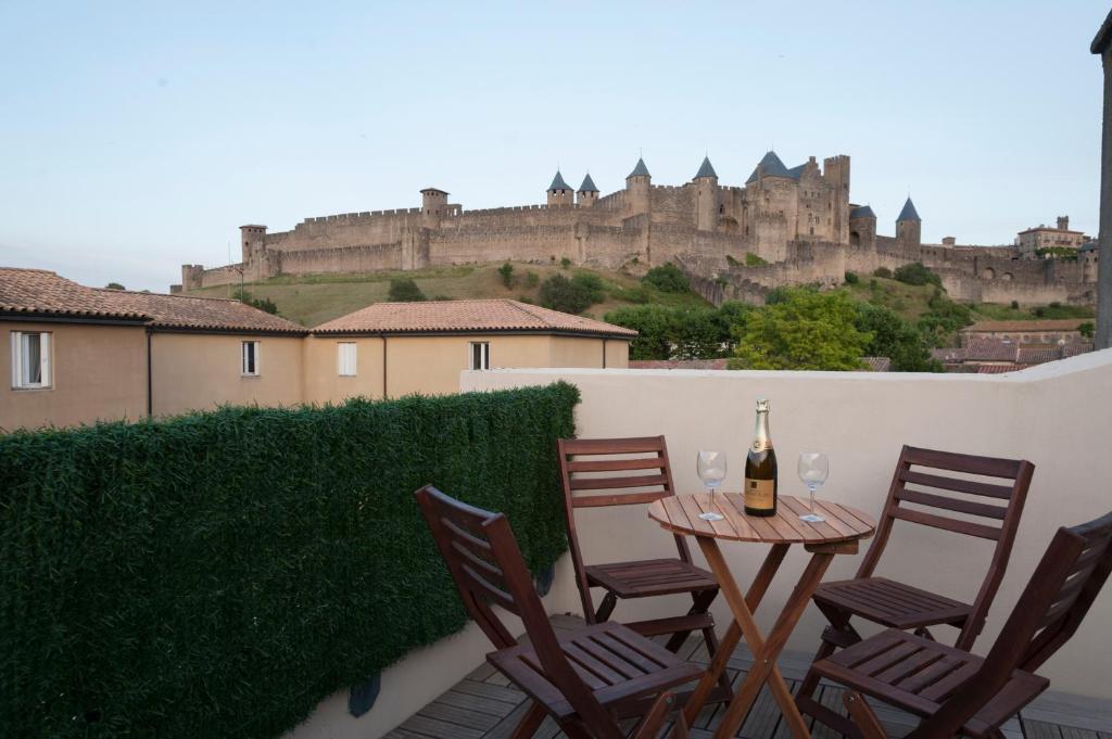 een patio met een tafel en stoelen met een kasteel op de achtergrond bij La Terrasse de Jules in Carcassonne