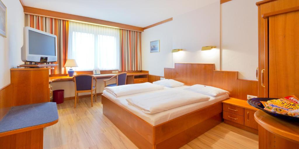 ウィーンにあるVienna Sporthotelのベッドとデスクが備わるホテルルームです。