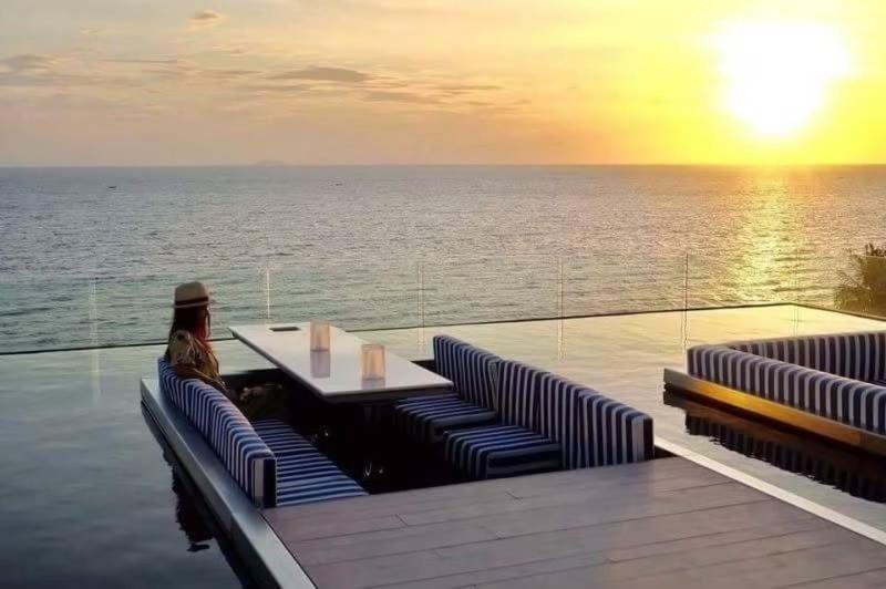 una mujer sentada en una cubierta viendo la puesta de sol en Veranda Residence Pattaya 112, en Na Jomtien