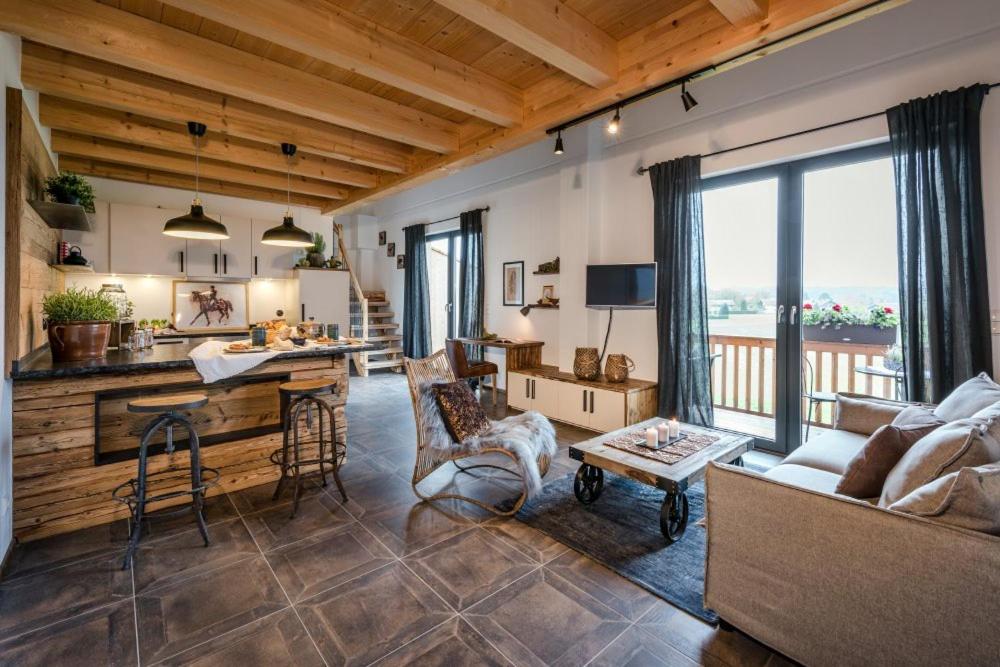 ein Wohnzimmer mit einem Sofa und einem Tisch sowie eine Küche in der Unterkunft Ferienwohnungen Gut Fasanenhöhe in Chieming
