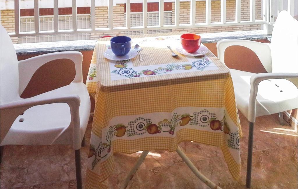 une table avec un chiffon de table jaune et blanc dans l'établissement Stunning Apartment In San Pedro Del Pinatar With Wifi, à San Pedro del Pinatar