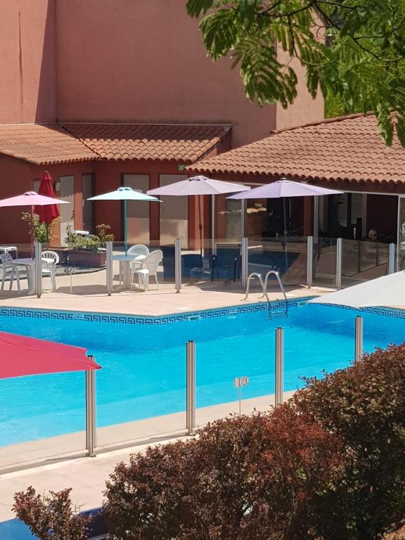 una piscina con mesas y sombrillas en un hotel en Albatros Appart 40 m2, 2 pièces près côte d'azur, piscine, parking, proche du Golf St Donat en Mouans-Sartoux