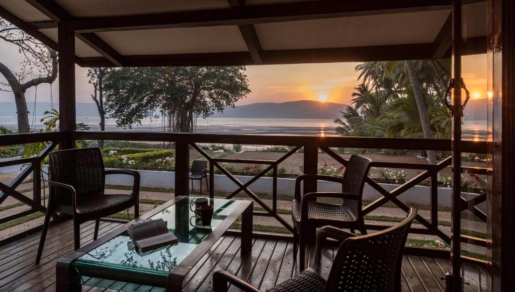 a porch with chairs and a table with a view of the ocean at SaffronStays Little Paradise, Murud in Murud