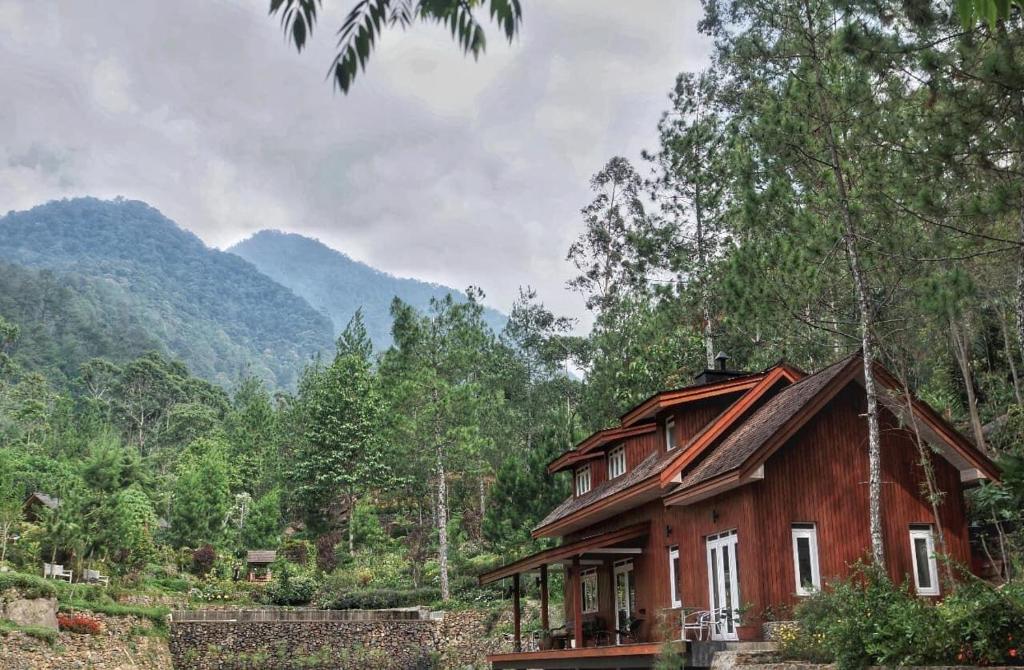 a house in a forest with mountains in the background at Mooi Lake House Luxury Villa in Malabar