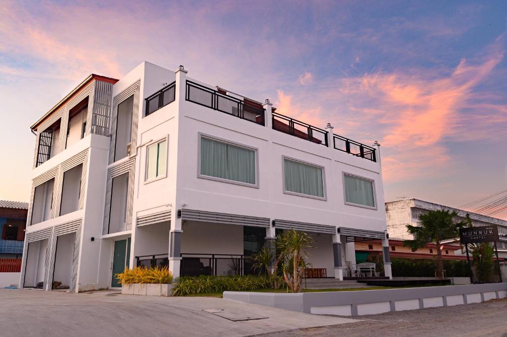 een wit gebouw met een balkon erboven bij Munruk Hostel in Prachuap Khiri Khan