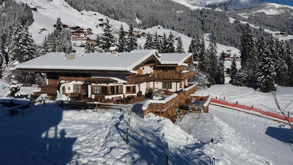 une grande maison en bois dans la neige sur une montagne dans l'établissement Ferienhof Ausserbrente, à Tux