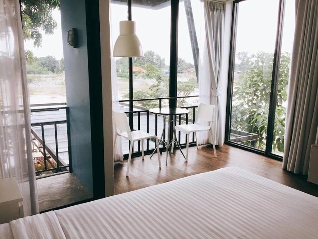 a bedroom with a bed and a table and chairs at Baan Khun Nine in Ratchaburi