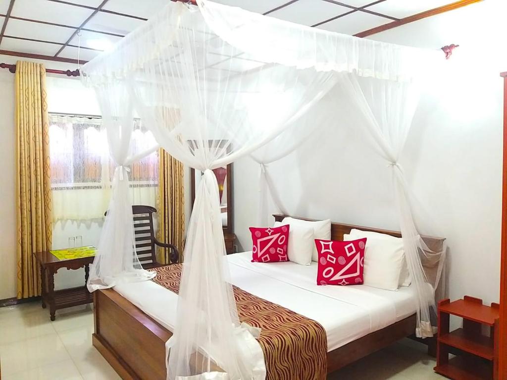 a bedroom with a canopy bed with red pillows at Sahana Sri Villa in Bentota