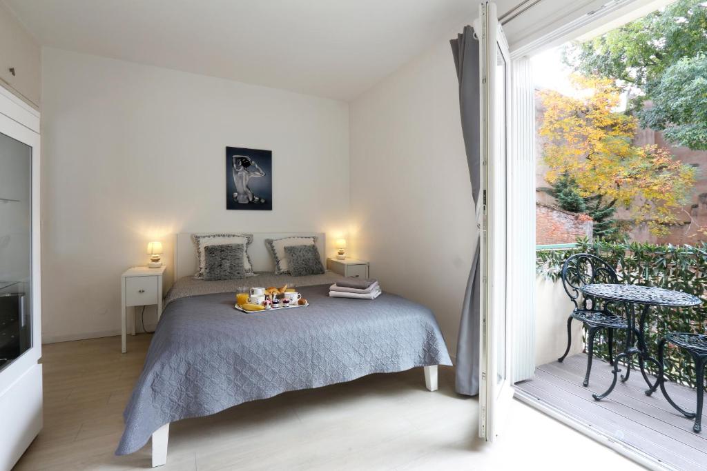 ein weißes Schlafzimmer mit einem Bett und einem Balkon in der Unterkunft Riverside Toulouse (Harmony) in Toulouse