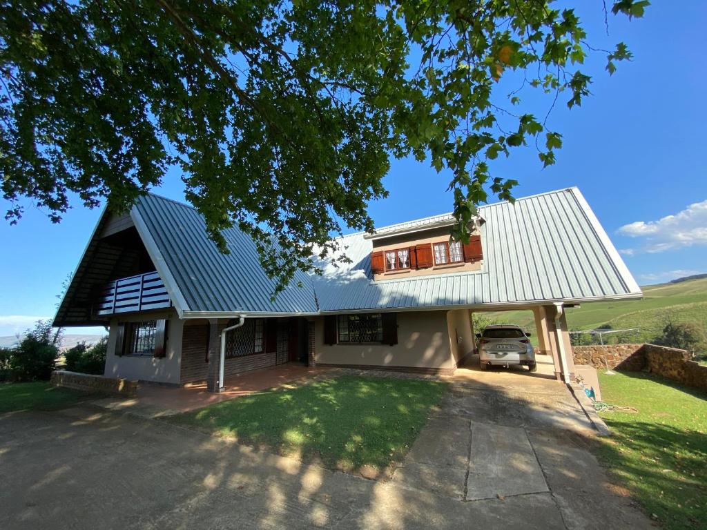 una casa con techo de metal y un coche aparcado delante en Drakensberg Dream, Champagne Valley, en Champagne Valley
