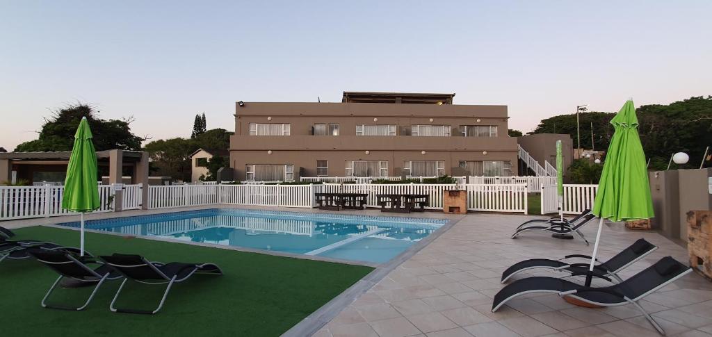 una piscina con sillas y sombrillas junto a un edificio en Falling Waters Guest House en Margate