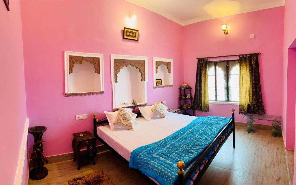 um quarto com paredes cor-de-rosa e uma cama com um cobertor azul em The Castle View Homestay em Bundi