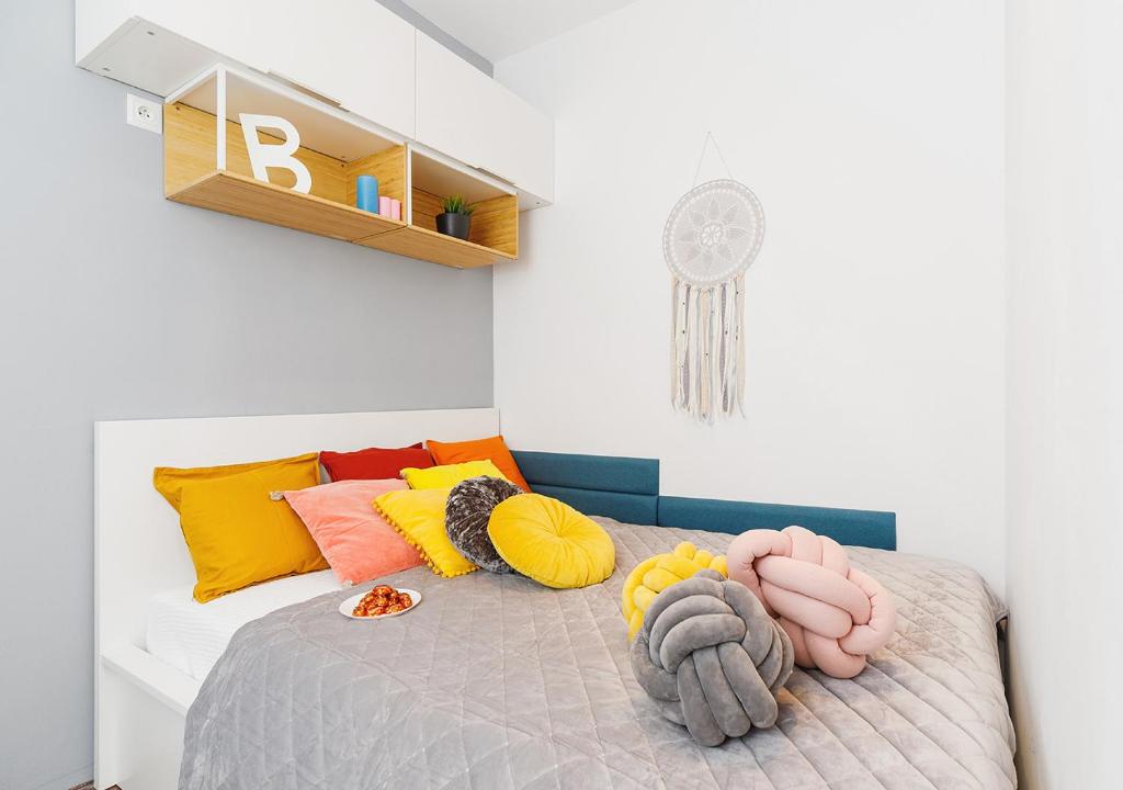 um pequeno quarto com uma cama com almofadas coloridas em Centre Apartments-Old Town em Cracóvia