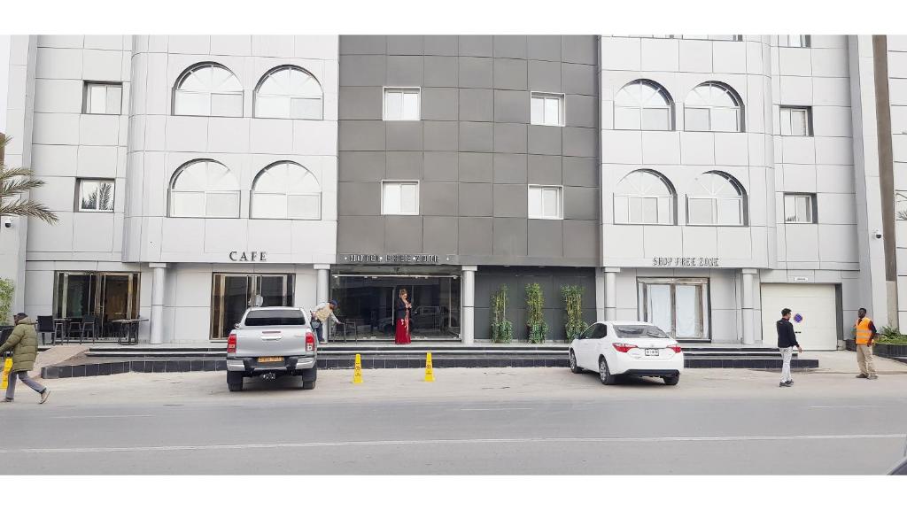 dos coches estacionados frente a un edificio en Hotel Free Zone en Nuadibú