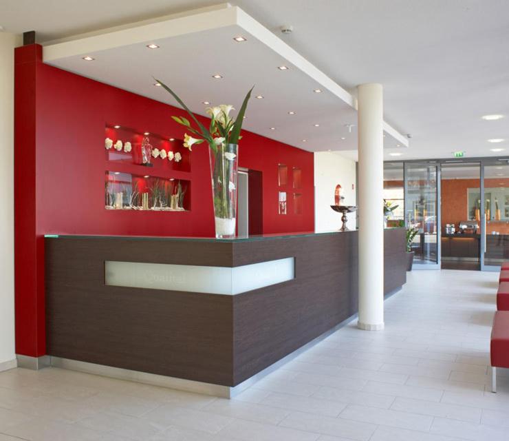 a lobby with a counter with a vase of flowers on it at Qualitel Wilnsdorf in Wilnsdorf