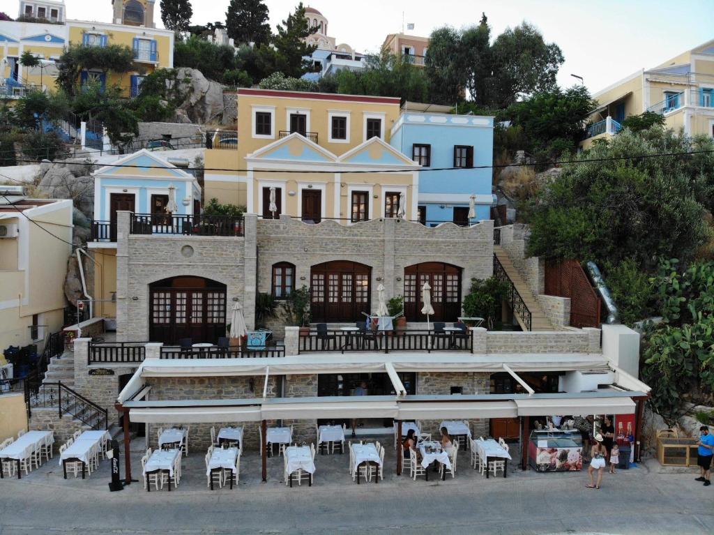 a building with tables and chairs in front of it at Odyssia in Symi