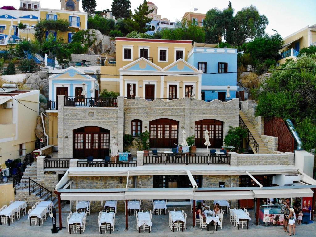 a building with tables and chairs in front of it at Odyssia in Symi