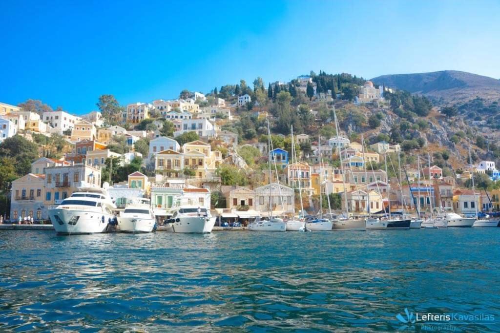 a group of boats docked in a harbor with houses at Odyssia in Symi